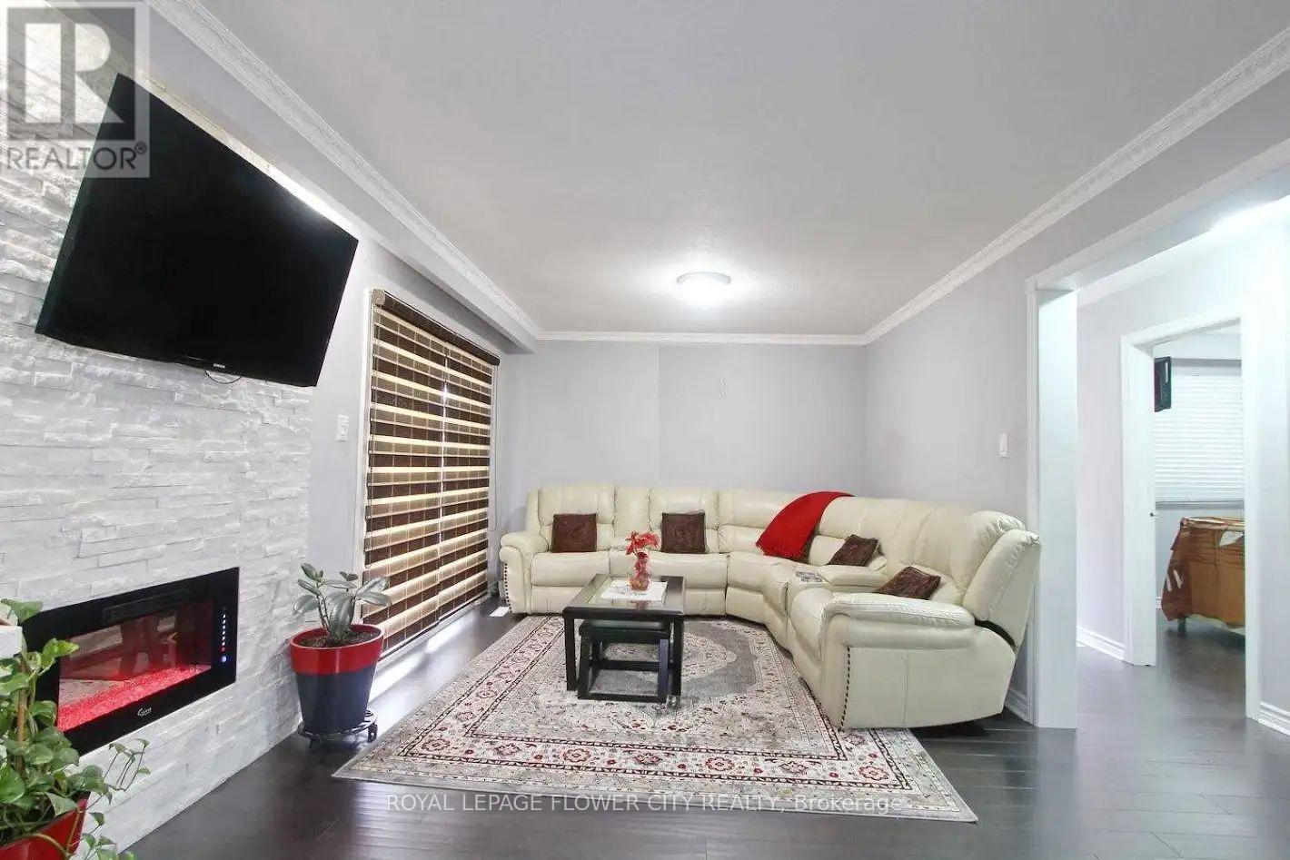 A living room with a white couch, a fireplace, and a flat screen TV mounted on the wall.