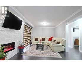 A living room with a white couch, a fireplace, and a flat screen TV mounted on the wall.