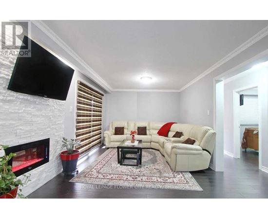 A living room with a white couch, a fireplace, and a flat screen TV mounted on the wall.