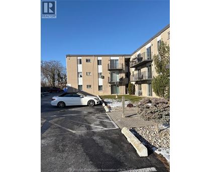 A white car is parked in a parking lot in front of a building.