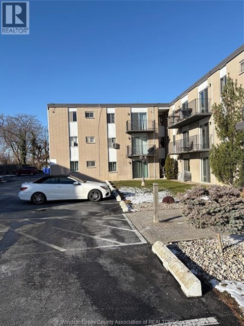 A white car is parked in a parking lot in front of a building.