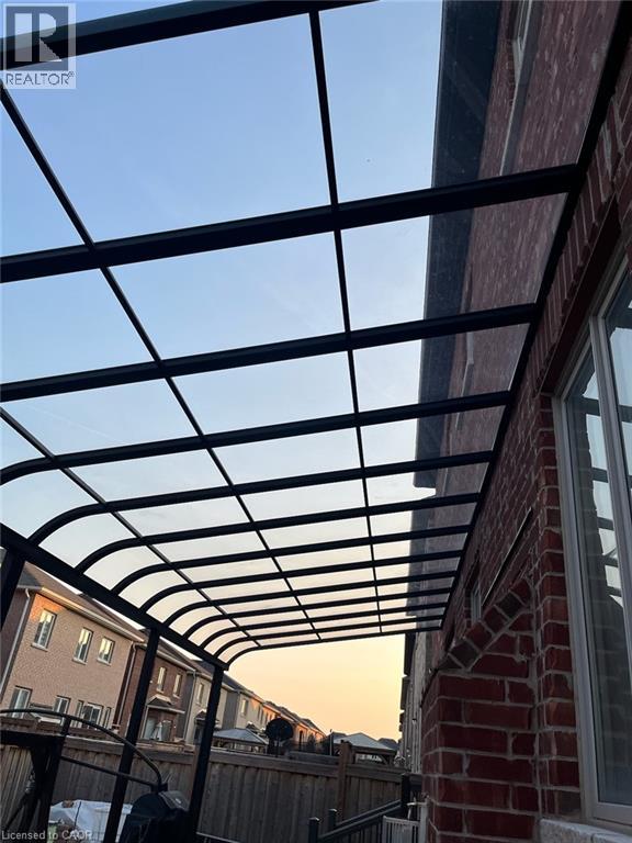 A pergola attached to a brick building with a clear sky in the background.