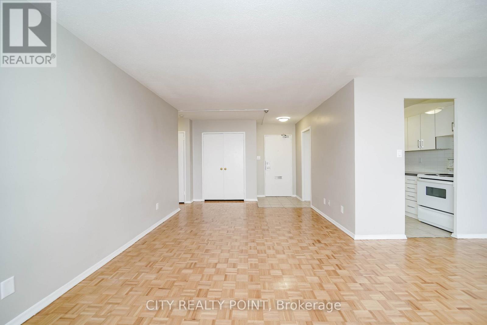 A spacious room with wooden flooring and white walls.