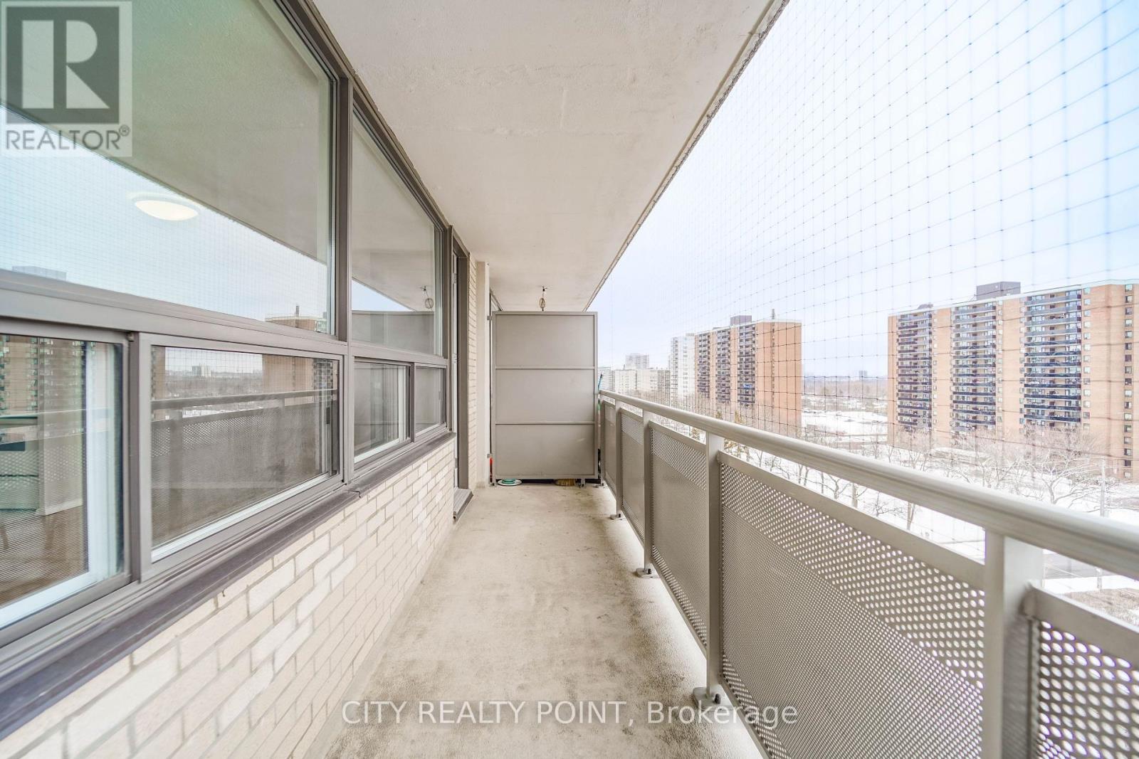 A balcony with a mesh screen and a view of apartment buildings.