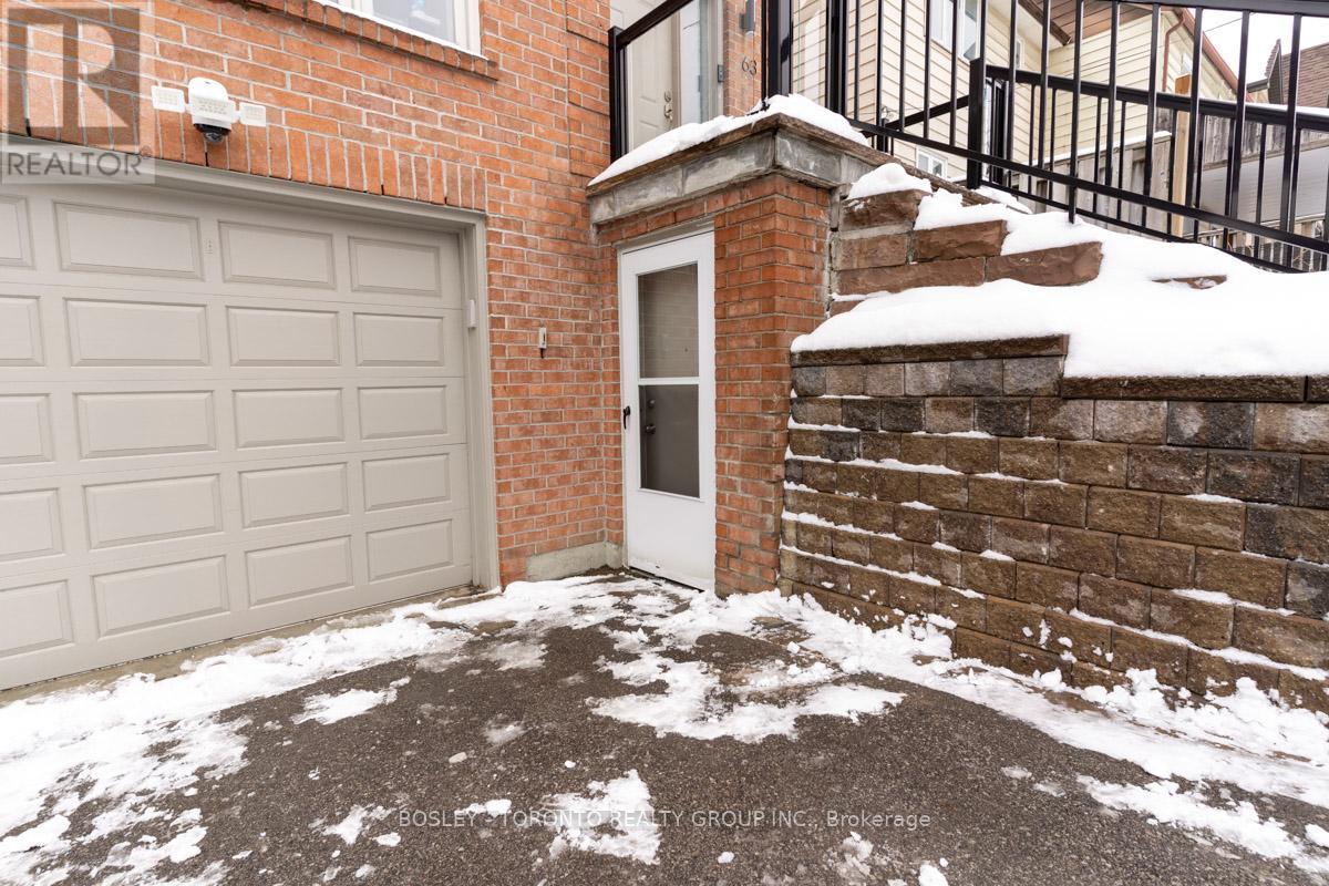 A snow-covered driveway leads to a brick house with a white garage door.