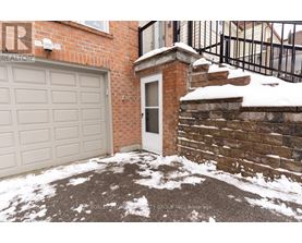 A snow-covered driveway leads to a brick house with a white garage door.