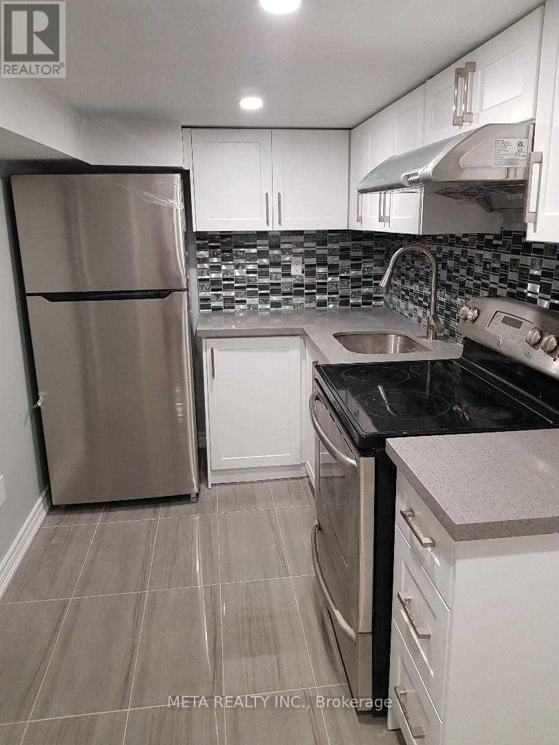 A kitchen with a refrigerator, sink, and stove.