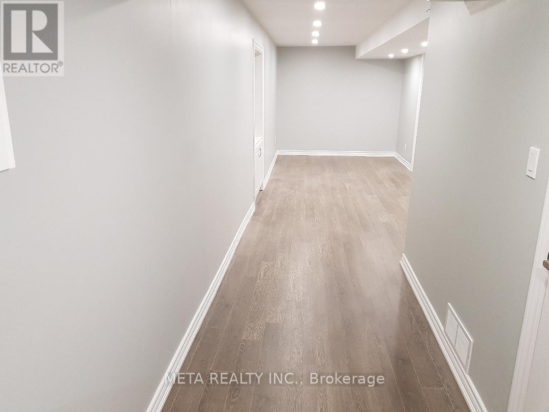A long hallway with wood flooring and white walls.
