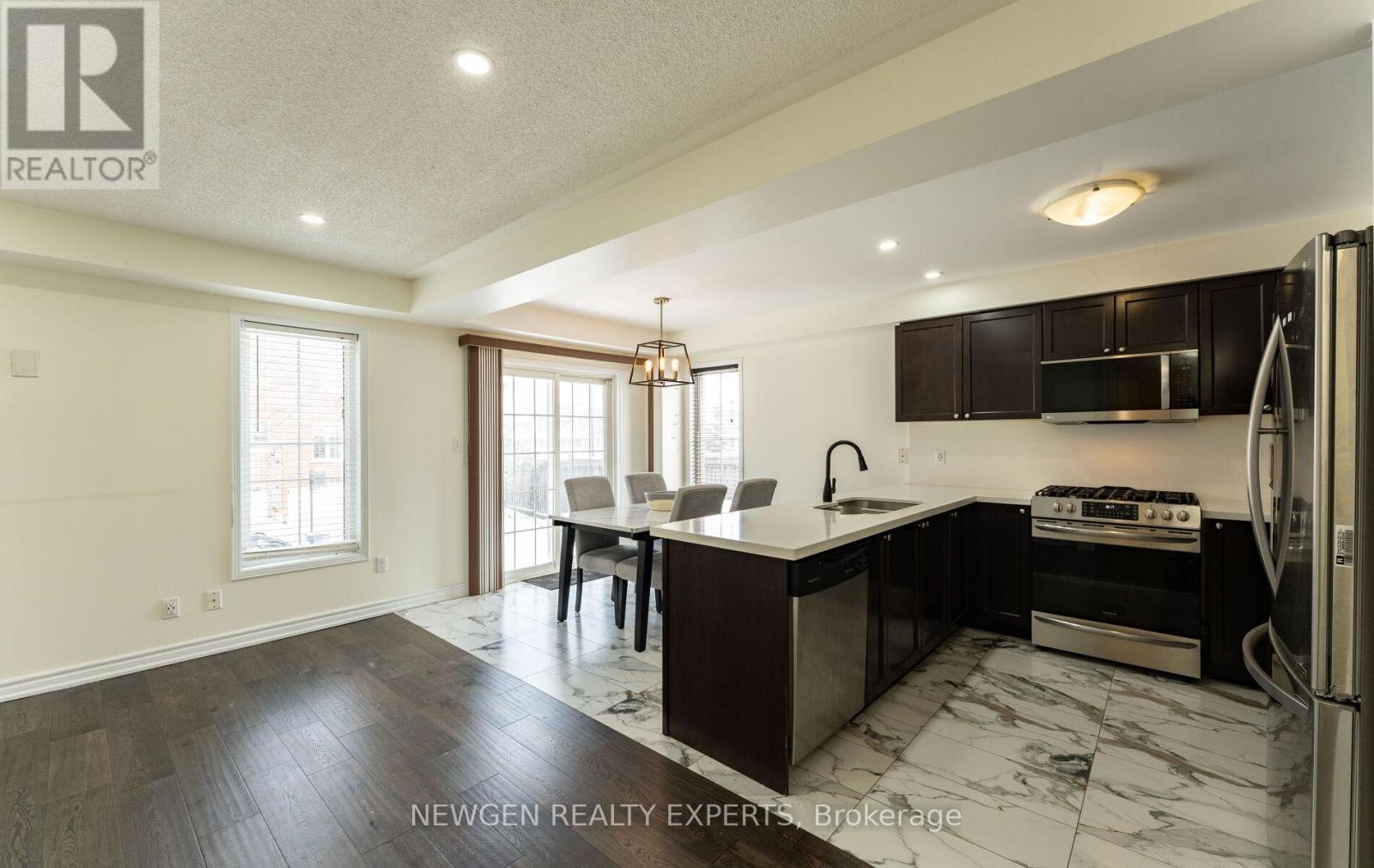 A modern kitchen with dark wood cabinets and a marble countertop.
