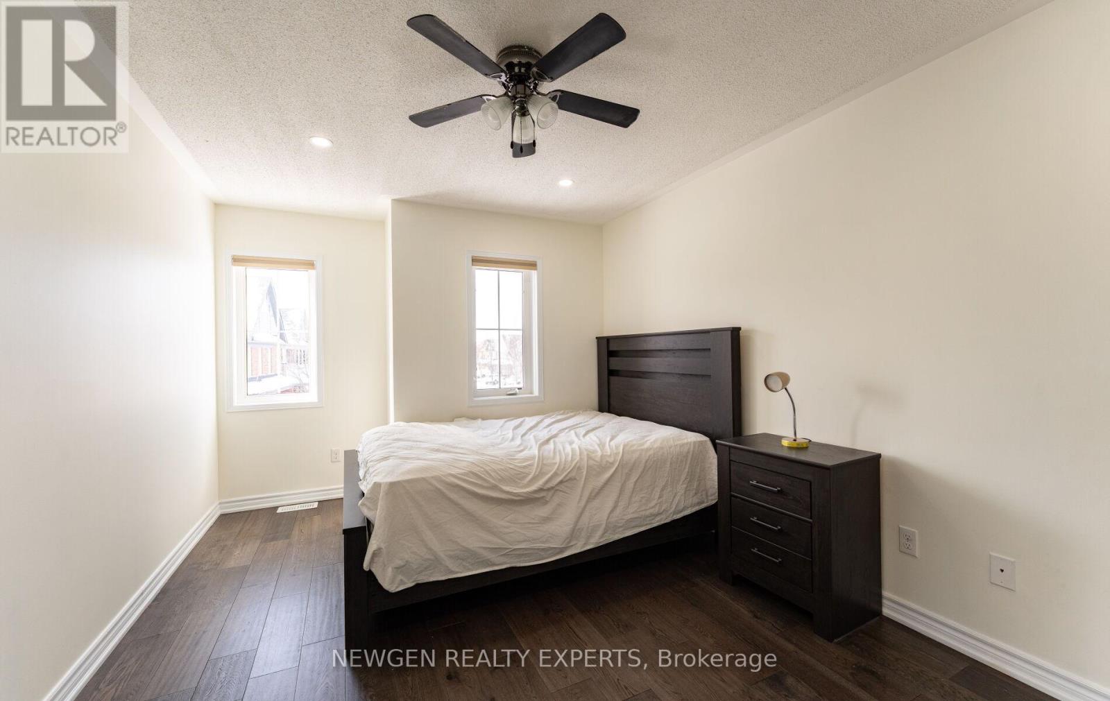 A bedroom with a bed, nightstand, and a ceiling fan.