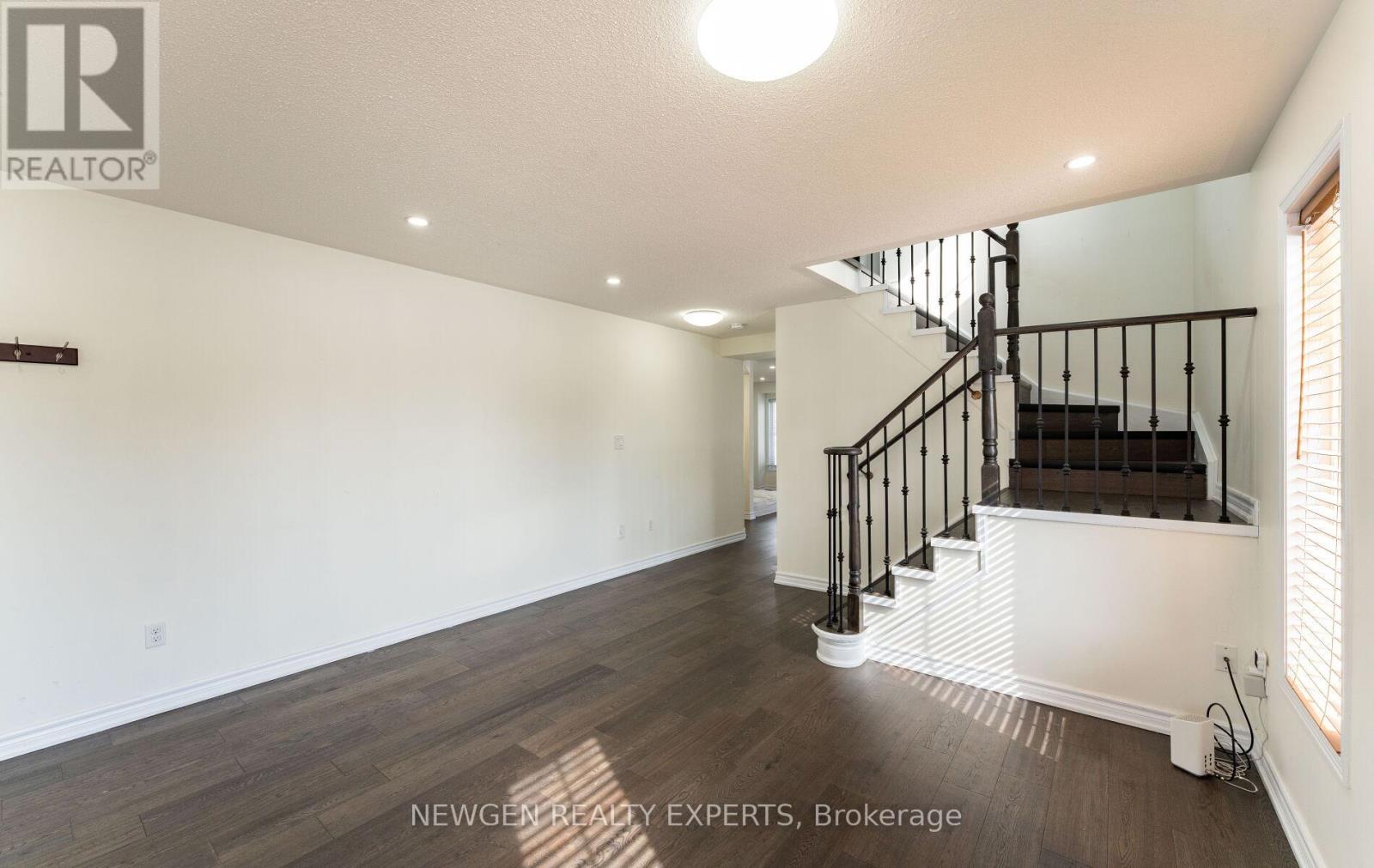 A spacious room with a staircase and wooden flooring.