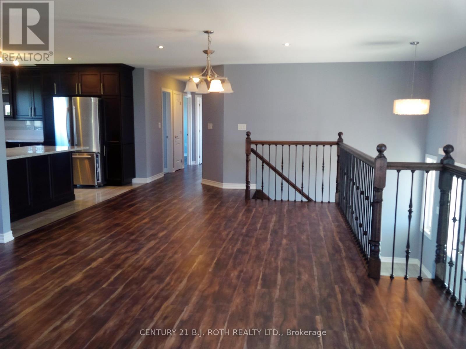 A large open space with wood flooring and a staircase with a metal railing.