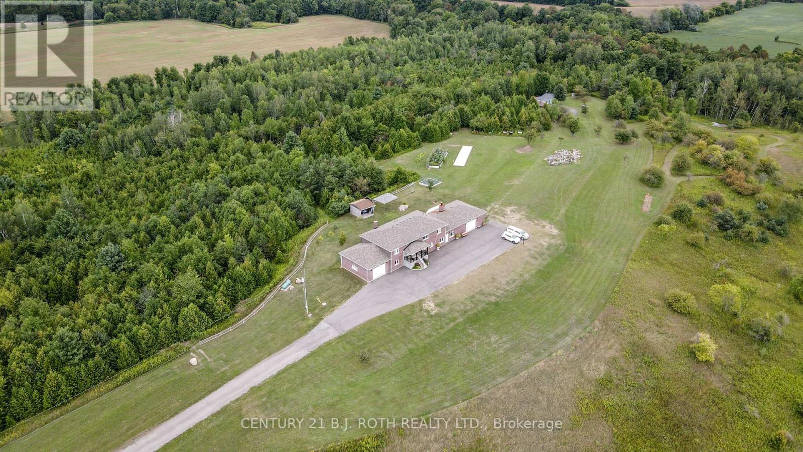 An aerial view of a property with a house and a driveway surrounded by trees.