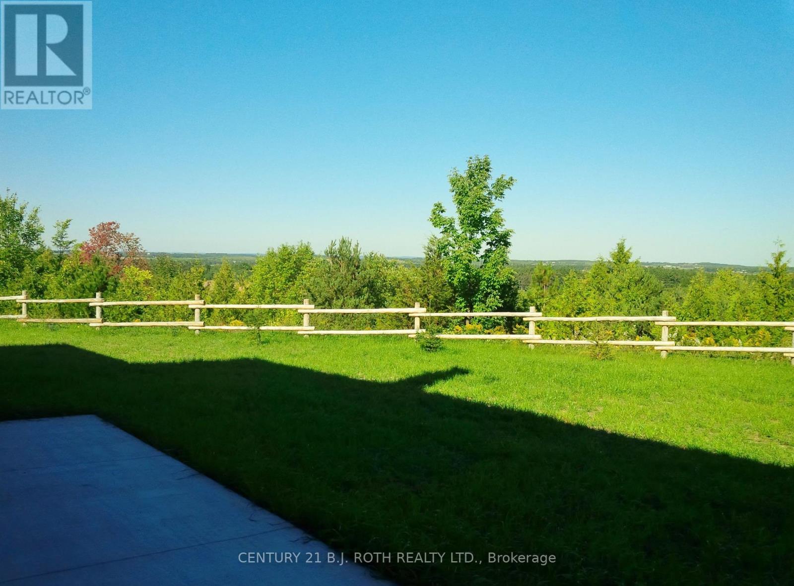 A bright sunny day at a property with a pool and a white fence.