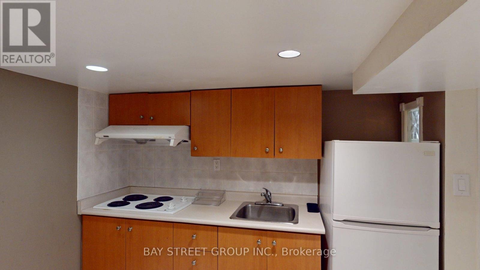 A kitchen with a white refrigerator and brown cabinets.