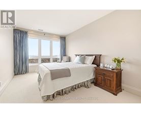 A bedroom with a large bed and a wooden cabinet.