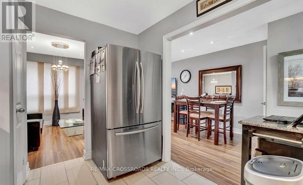 A modern kitchen with a stainless steel refrigerator and wooden flooring.