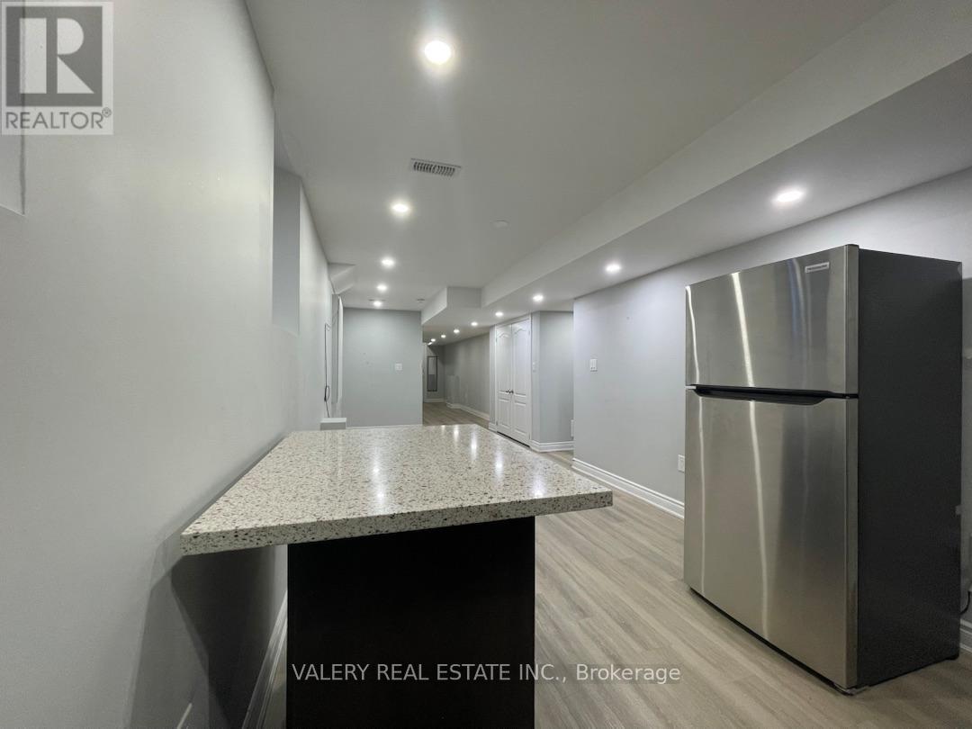 A kitchen with a stainless steel refrigerator and a granite countertop.