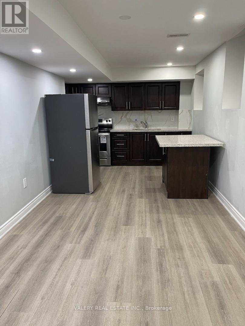 A kitchen with a refrigerator, cabinets, and a countertop.