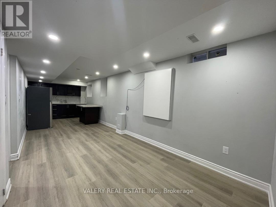 A room with wood flooring and white walls, with a logo for REALTOR on the top left.