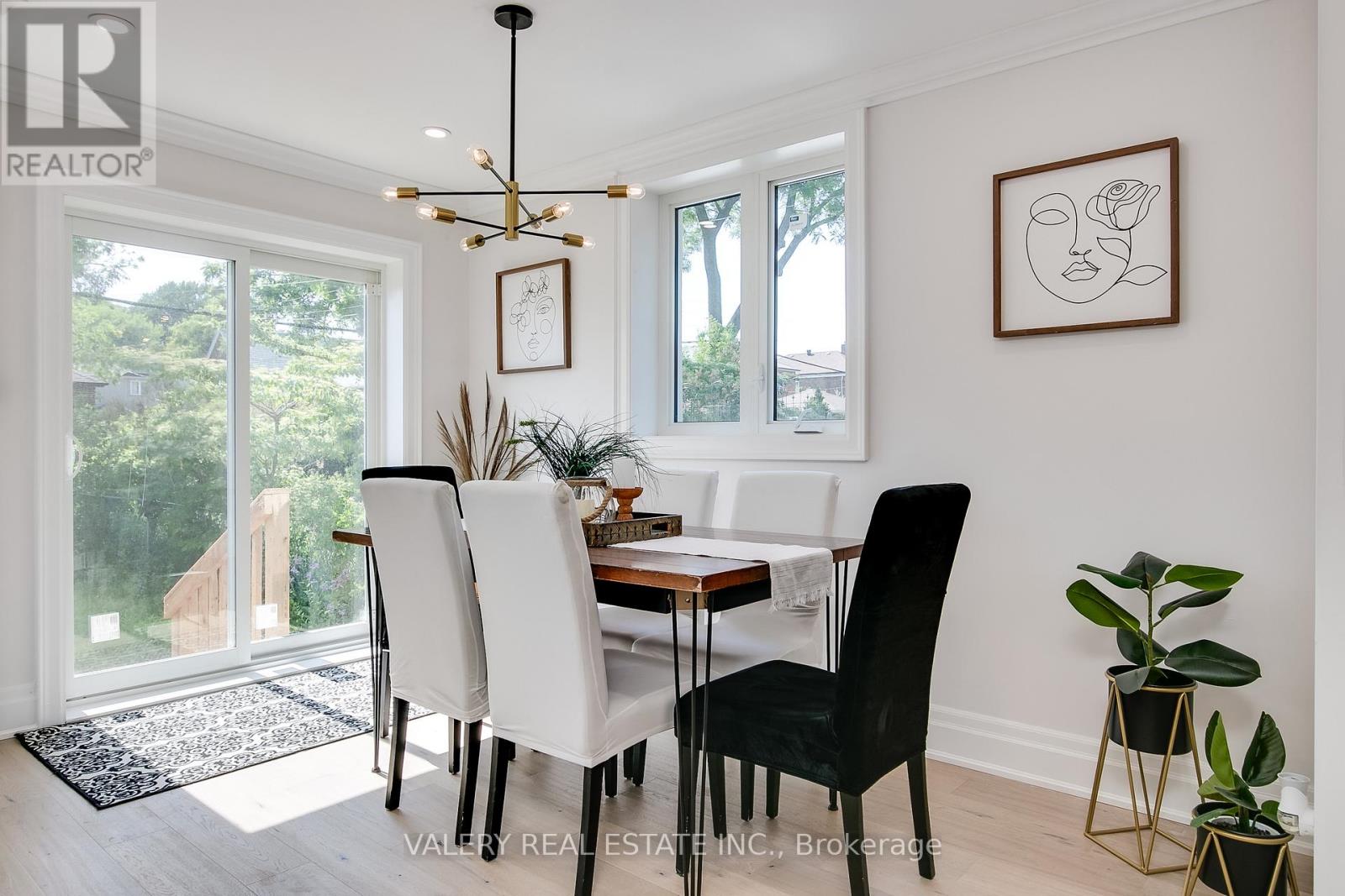 A dining room with a table set for two and a plant on the side table.