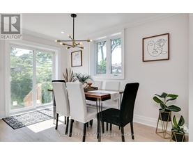 A dining room with a table set for two and a plant on the side table.