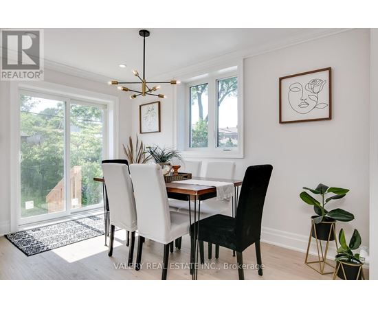 A dining room with a table set for two and a plant on the side table.