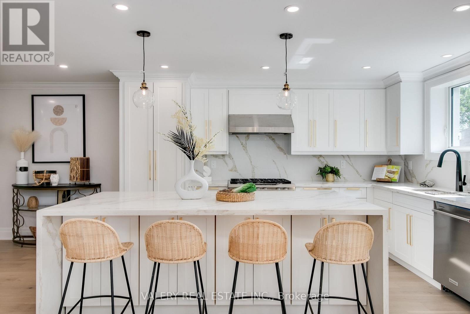 A modern kitchen with white cabinets and a central island with three chairs.