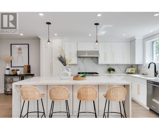 A modern kitchen with white cabinets and a central island with three chairs.