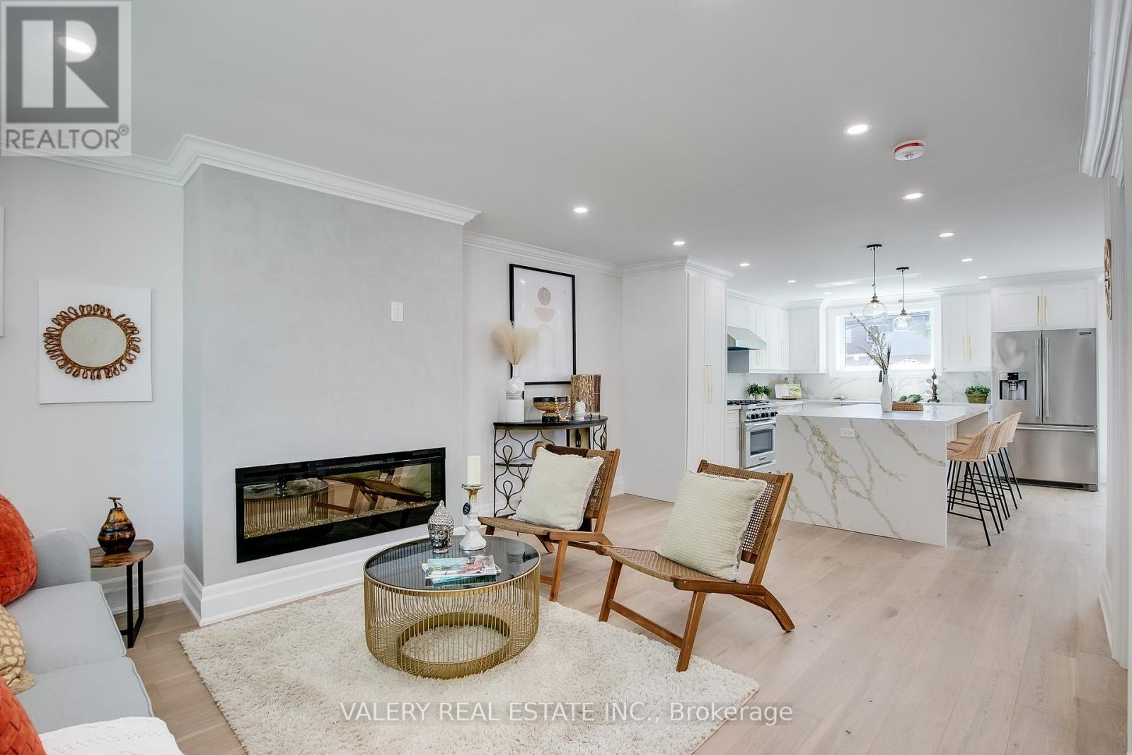A living room with a fireplace and a dining area in the background.