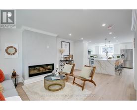 A living room with a fireplace and a dining area in the background.