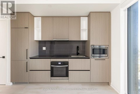 A modern kitchen with wooden cabinets and black countertops.