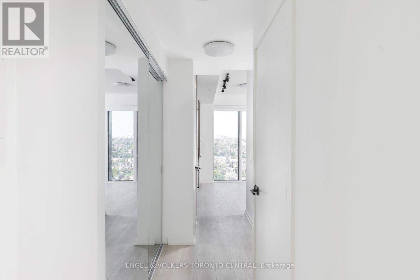 A white hallway with a door on the right and a window on the left.