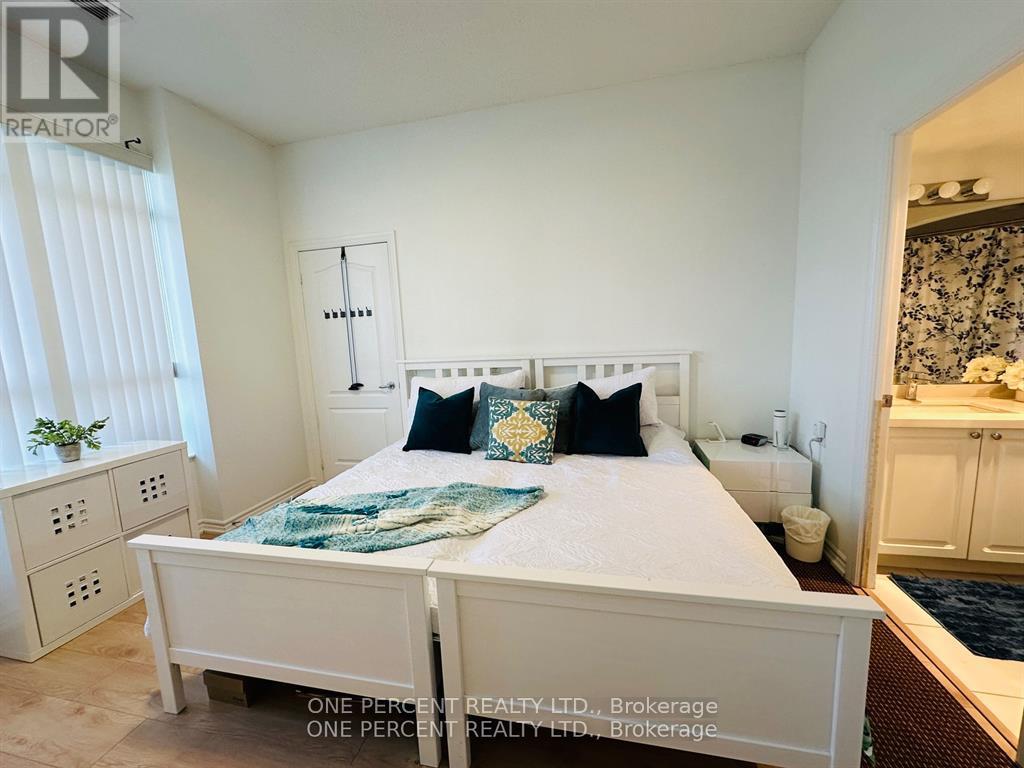 A bedroom with a large bed and a window with blinds.