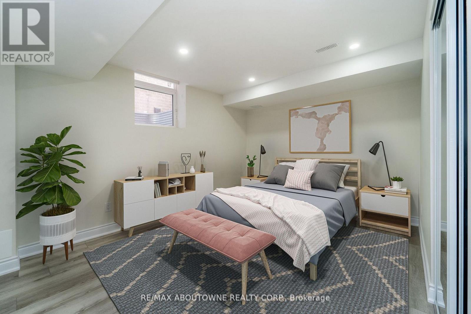 A bedroom with a bed, nightstand, and a plant.