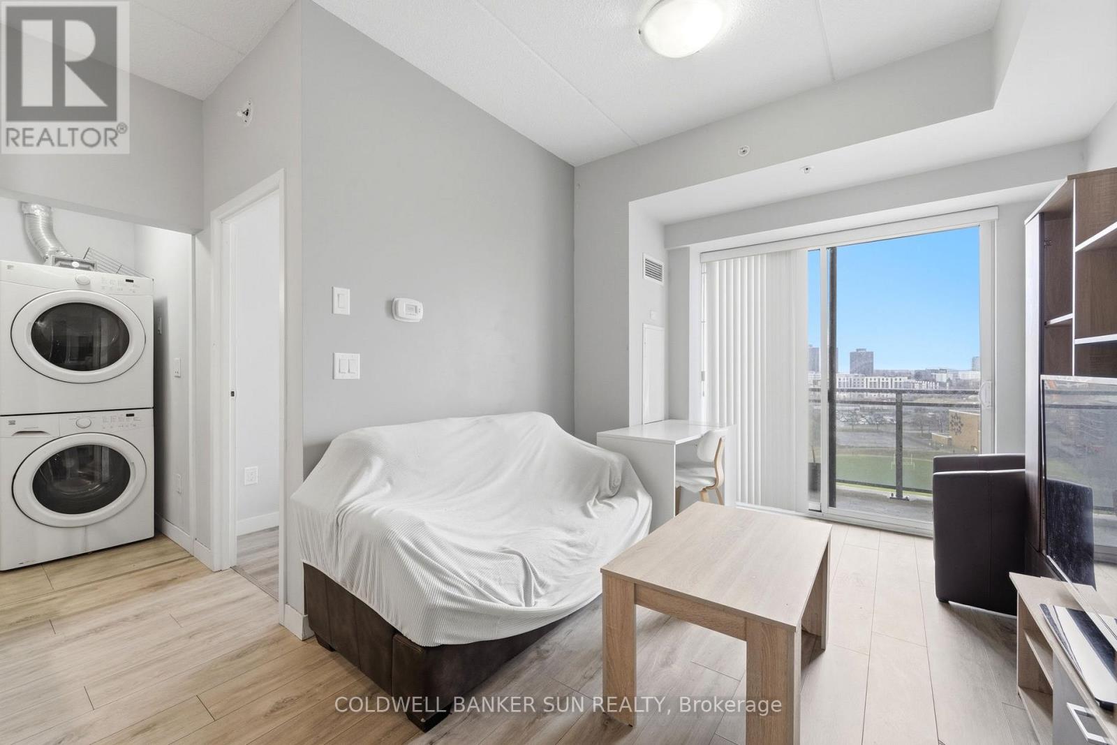 A bedroom with a bed covered in a white sheet, a washing machine, and a dryer in the corner.