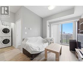 A bedroom with a bed covered in a white sheet, a washing machine, and a dryer in the corner.