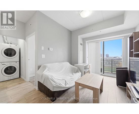 A bedroom with a bed covered in a white sheet, a washing machine, and a dryer in the corner.