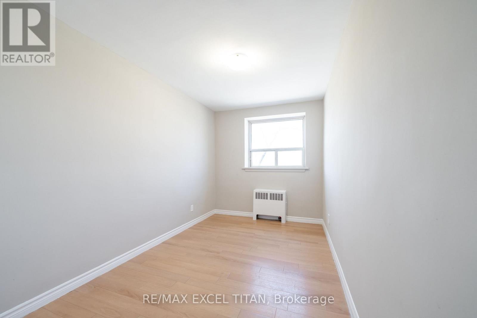 A small room with a window and a radiator on the wall.
