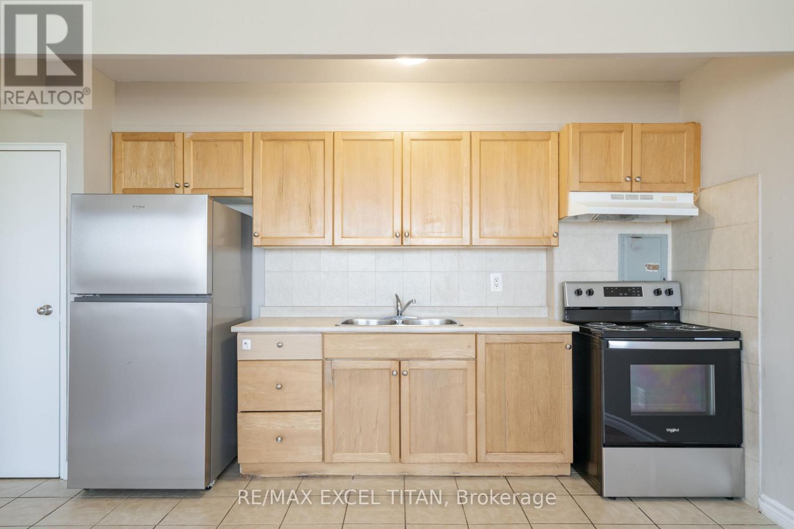 A kitchen with wooden cabinets and a stainless steel refrigerator.