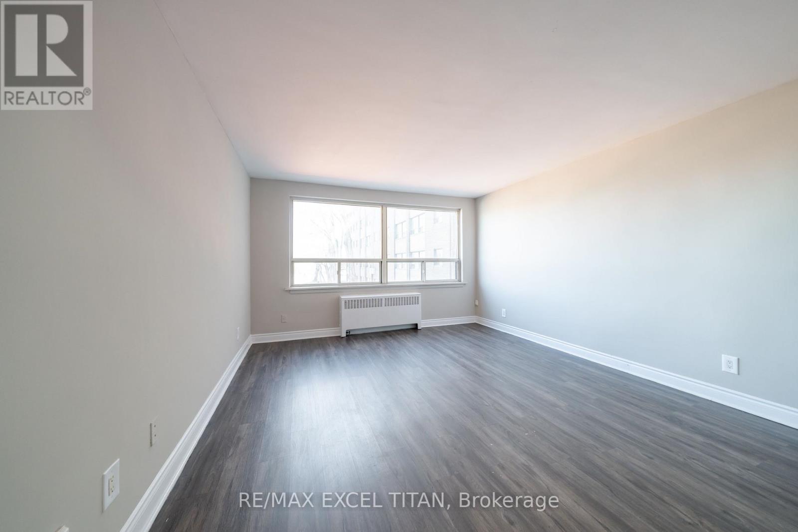 A large, empty room with a window and radiator.