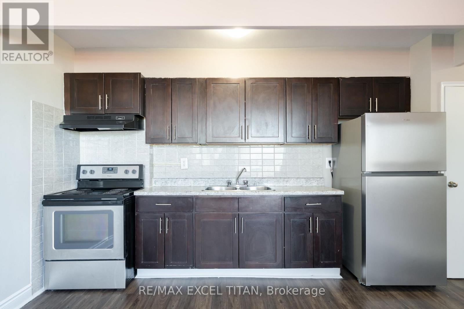 A kitchen with dark brown cabinets and stainless steel appliances.