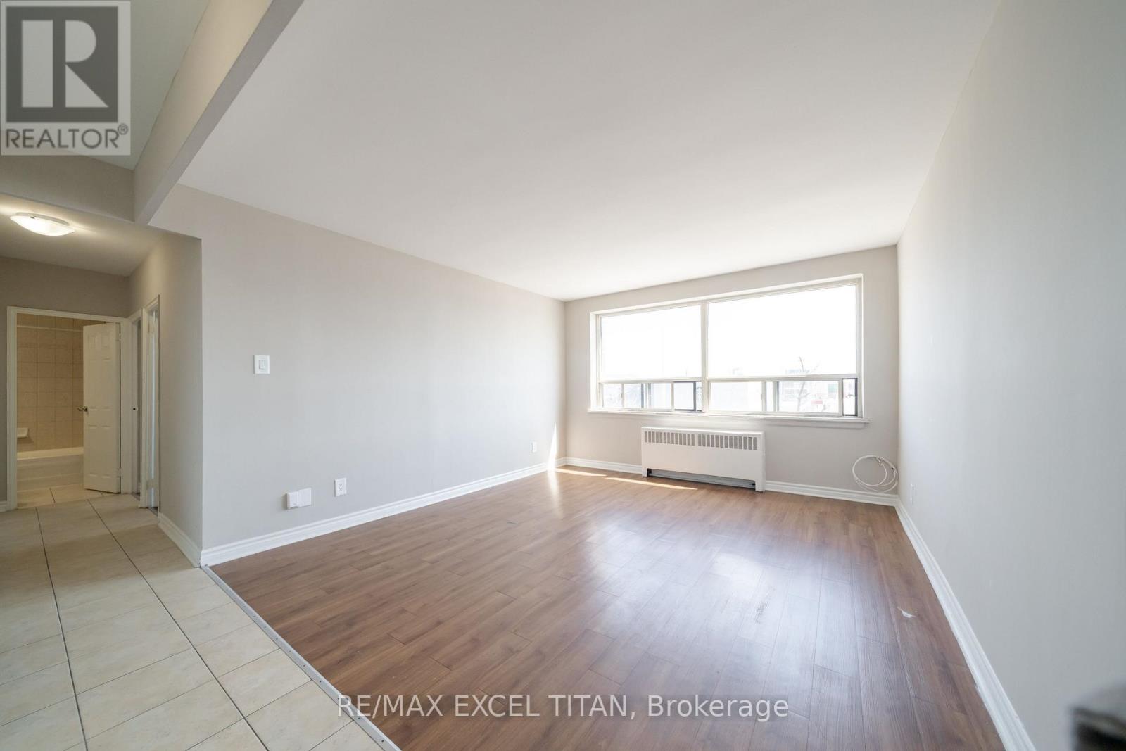A spacious room with wooden flooring and a large window.