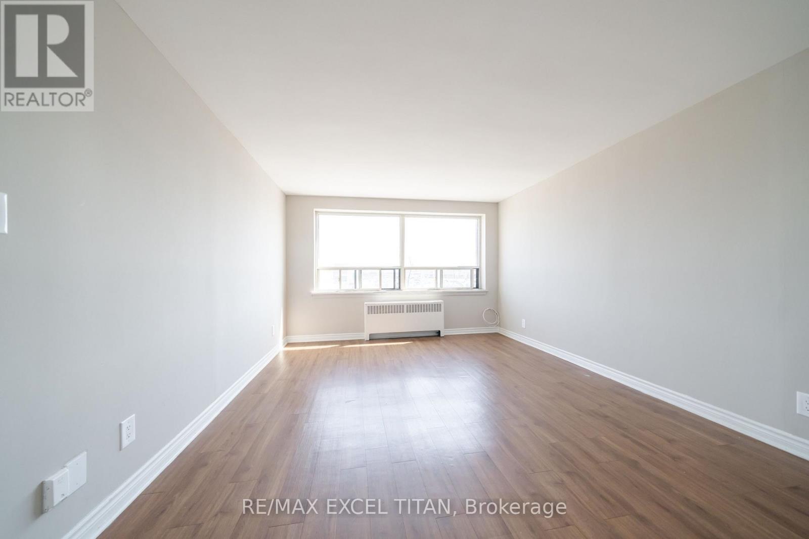 A large, empty room with a window and radiator.