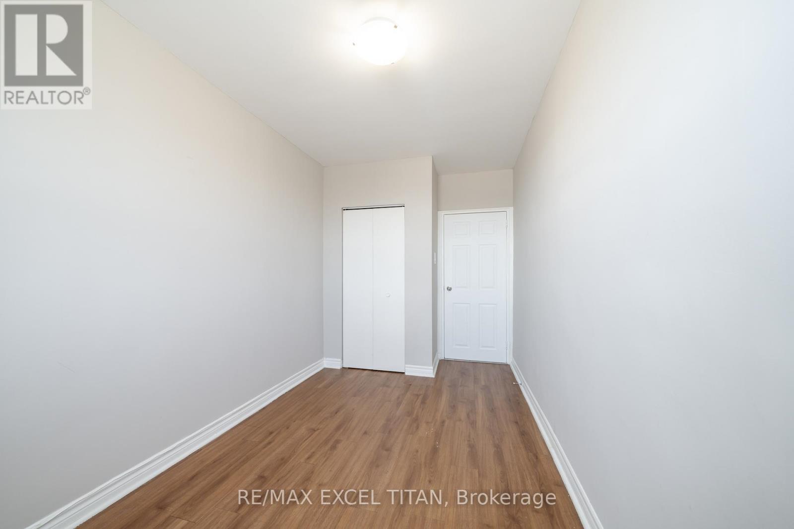 A white hallway with wood floors and two doors.