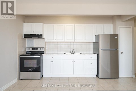 A white kitchen with a refrigerator, oven, and sink.