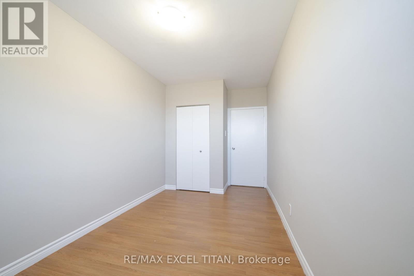 A white room with a wooden floor and two white doors.