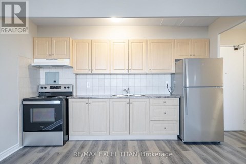 A kitchen with a refrigerator, oven, and sink.
