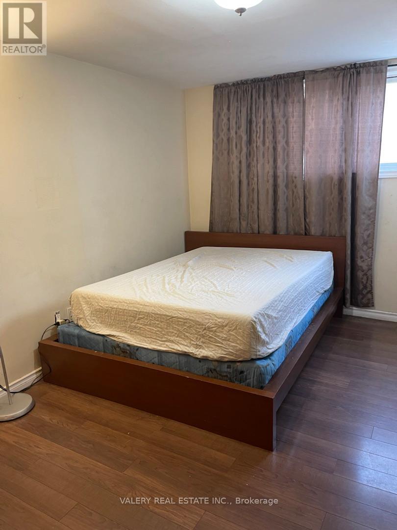 A bedroom with a bed, wooden headboard, and curtains.