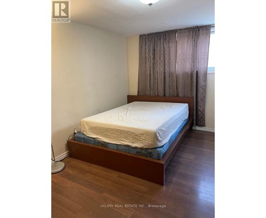 A bedroom with a bed, wooden headboard, and curtains.